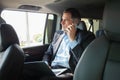 Handsome businessman talking with phone sitting with laptop on the backseat of the car. Royalty Free Stock Photo