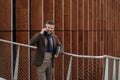 Handsome businessman talking on smart phone and smiling on a terrace outside office, working. Royalty Free Stock Photo