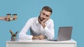 Handsome businessman tired of computer work sleeping at his desk on blue studio background, panorama