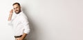 Handsome businessman turn at camera and looking confident, smiling cheeky, standing over white background