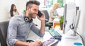 Handsome businessman using a computer, talking on the mobile phone and smiling while working in office. Royalty Free Stock Photo