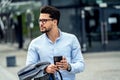 Handsome businessman using mobile phone app outside of office. Successful man holding smartphone for business work Royalty Free Stock Photo