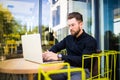 Handsome businessman using modern laptop outdoors, successful manager working in cafe during break and searching information in in Royalty Free Stock Photo