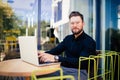 Handsome businessman using modern laptop outdoors, successful manager working in cafe during break and searching information in in Royalty Free Stock Photo