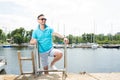 Handsome businessman on vacation with yachts on dock background. Sport Man in sunglasses laddering up on boat Royalty Free Stock Photo