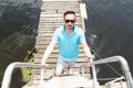 A Handsome businessman on vacation with yachts on dock and wooden pier background. Man in sunglasses laddering up Royalty Free Stock Photo