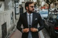 Handsome businessman walking on the sidewalk and buttoning jacket Royalty Free Stock Photo