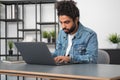 Handsome businessman wearing casual wear is sitting typing on laptop