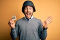 Handsome businessman wearing military helmet holding reminder paper with war message very happy and excited, winner expression Royalty Free Stock Photo