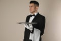 Handsome butler with tray on beige background