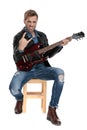 Seated man playing his guitar aggressively Royalty Free Stock Photo