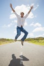 Handsome casual man leaping on a road smiling at camera Royalty Free Stock Photo