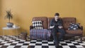 Handsome casual young man using a tablet at home sitting on a sofa in his living room, browsing the internet. Stock Royalty Free Stock Photo