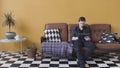 Handsome casual young man using a tablet at home sitting on a sofa in his living room, browsing the internet. Stock Royalty Free Stock Photo