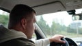 Handsome Caucasian adult man driving a car on highway and looking on sides. Rear view. Close up. Male holding hand on Royalty Free Stock Photo