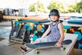 A handsome caucasian boy in a helmet sits on a ramp in a skate park. A skateboarder is resting between tricks. Athlete child break