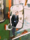 Handsome caucasian business man in black suit looking at camera through rear view mirror of retro bus Royalty Free Stock Photo