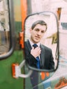 Handsome caucasian business man correcting his tie looking at rear view mirror of retro bus Royalty Free Stock Photo