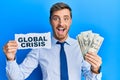 Handsome caucasian business man holding dollars on global crisis celebrating crazy and amazed for success with open eyes screaming Royalty Free Stock Photo