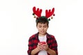 Handsome Caucasian child boy wearing deer antler hoop on head, holds a lit candle, makes a cherished wish for Christmas