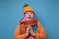 Handsome funny senior man in several hats and scarfs looking up in surprise