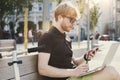 Handsome caucasian hipster man using mobile phone sitting outdoor in a park. Summer sunshine day. Concept of young business people Royalty Free Stock Photo