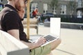 Handsome caucasian hipster man working on laptop sitting outdoor in a park. Summer sunshine day. Concept of young business people Royalty Free Stock Photo