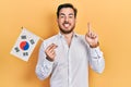 Handsome caucasian man with beard holding south korea flag smiling with an idea or question pointing finger with happy face, Royalty Free Stock Photo