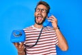 Handsome caucasian man with beard holding vintage telephone angry and mad screaming frustrated and furious, shouting with anger Royalty Free Stock Photo