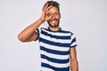Handsome caucasian man with beard wearing casual striped t-shirt smiling happy doing ok sign with hand on eye looking through Royalty Free Stock Photo