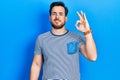 Handsome caucasian man with beard wearing casual striped t shirt smiling positive doing ok sign with hand and fingers Royalty Free Stock Photo