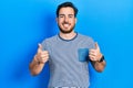 Handsome caucasian man with beard wearing casual striped t shirt success sign doing positive gesture with hand, thumbs up smiling Royalty Free Stock Photo