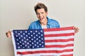 Handsome caucasian man holding united states flag smiling and laughing hard out loud because funny crazy joke