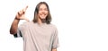 Handsome caucasian man with long hair wearing casual clothes smiling and confident gesturing with hand doing small size sign with Royalty Free Stock Photo