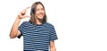 Handsome caucasian man with long hair wearing casual striped t-shirt smiling and confident gesturing with hand doing small size Royalty Free Stock Photo