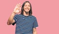 Handsome caucasian man with long hair wearing casual striped t-shirt smiling positive doing ok sign with hand and fingers Royalty Free Stock Photo