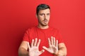 Handsome caucasian man wearing casual red tshirt moving away hands palms showing refusal and denial with afraid and disgusting Royalty Free Stock Photo