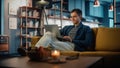 Handsome Caucasian Man Working on Laptop Computer while Sitting on a Sofa in Stylish Cozy Living