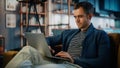 Handsome Caucasian Man Working on Laptop Computer while Sitting on a Sofa in Stylish Cozy Living