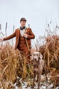 Young man hunter on the hunting field with hunter dog heading for hunt. Dog waiting for the shot Royalty Free Stock Photo