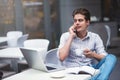 Confident young man in smart casual wear holding a cup and talking by smartphone. Royalty Free Stock Photo