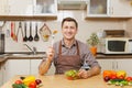 Handsome caucasian young man, sitting at table. Healthy lifestyle. Cooking at home. Prepare food. Royalty Free Stock Photo