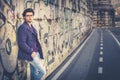 Handsome and charming young man outdoors leans against a wall in the city