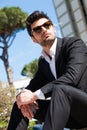 Handsome and charming young man with sunglasses sitting outdoors