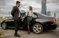 Handsome man holding car door for beautiful businesswoman Royalty Free Stock Photo