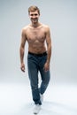 Handsome cheerful man. Full length of handsome young shirtless man in jeans looking at camera with smile while standing Royalty Free Stock Photo