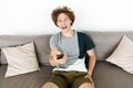 Handsome cheerful man sitting on sofa holding remote control