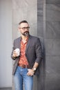 Handsome cheerful man standing near office building holding disposable cup coffee Royalty Free Stock Photo