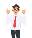Handsome cheerful young business man showing/gesturing/making okay or ok sign with two hands and fingers. Human emotions, facial.