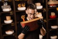 Handsome cheese sommelier holding and jokes with limited gouda cheese. Snack tasty piece of cheese for appetizer. Hungry